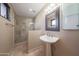 Bright bathroom features a pedestal sink and a glass enclosed shower with travertine tile surround at 2718 E Campo Bello Dr, Phoenix, AZ 85032