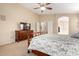 Cozy bedroom featuring a dresser, TV, ceiling fan, and an open doorway to the ensuite bathroom at 41762 W Little Ct, Maricopa, AZ 85138