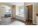 A light-filled bathroom showcasing wood floors, a soaking tub, and open access to a spacious bedroom at 53573 W Fresno Rd, Maricopa, AZ 85139