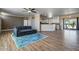 An open concept living space with wood flooring flows into the white cabinet kitchen with stainless steel appliances at 53573 W Fresno Rd, Maricopa, AZ 85139