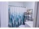 Clean bathroom featuring a patterned shower curtain, floating shelves, and a pristine white vanity at 5458 W El Caminito Dr, Glendale, AZ 85302