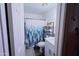 Clean bathroom featuring a patterned shower curtain, floating shelves, and a pristine white vanity at 5458 W El Caminito Dr, Glendale, AZ 85302