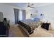 Bright bedroom featuring neutral carpet, modern ceiling fan, and a large bed with storage underneath at 5458 W El Caminito Dr, Glendale, AZ 85302