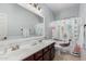 Bright bathroom featuring a double vanity sink, nautical themed shower curtain and neutral colored tile floor at 6931 W Antelope Dr, Peoria, AZ 85383