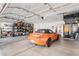 Spacious garage featuring an orange sports car, shelves, and a stainless steel refrigerator at 6931 W Antelope Dr, Peoria, AZ 85383
