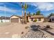 Single-story home with desert landscaping, palm trees, and a brown two-car garage, showcasing its curb appeal at 7454 E Pueblo Ave, Mesa, AZ 85208