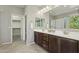 The main bathroom has a double sink vanity and a walk-in shower with white countertops and dark wood cabinets at 8516 W Peppertree Ln, Glendale, AZ 85305