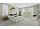 A staged bedroom has neutral paint, carpet, plenty of natural light, and simple decor at 8516 W Peppertree Ln, Glendale, AZ 85305