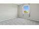 An empty, carpeted bedroom with a neutral color palette and natural light from the window at 8516 W Peppertree Ln, Glendale, AZ 85305