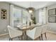 A formal dining room is staged with a wooden table, white chairs, light fixture, and an area rug on tile flooring at 8516 W Peppertree Ln, Glendale, AZ 85305