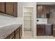 This kitchen features a walk-in pantry with white shelving and dark wood cabinets with granite countertops at 8516 W Peppertree Ln, Glendale, AZ 85305