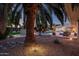 A tranquil backyard featuring a pool, spa, palm trees, and elegant outdoor seating at dusk at 9128 N 70Th St, Paradise Valley, AZ 85253