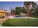 Lush backyard with putting green, pool featuring a rock waterfall, and plenty of mature palm trees at 9128 N 70Th St, Paradise Valley, AZ 85253