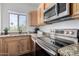 Close-up of kitchen with stainless steel appliances, granite countertops, and natural wood cabinets at 1411 E Orangewood Ave # 202, Phoenix, AZ 85020