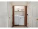 Laundry room with bi-fold doors, featuring washer, dryer, and storage shelving at 16350 N Desert Sage St, Surprise, AZ 85378