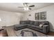 Inviting living room features a comfortable gray sofa, ceiling fan, and ample natural light at 16350 N Desert Sage St, Surprise, AZ 85378