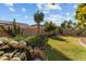 Expansive backyard offers privacy, lush lawn, mature trees, cacti, and a charming rock water feature at 20821 W Ridge Rd, Buckeye, AZ 85396
