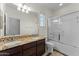 Bright bathroom with a double sink vanity, granite counters and a shower-tub combo with sliding glass doors at 20821 W Ridge Rd, Buckeye, AZ 85396