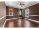 Cozy bedroom with three windows, a ceiling fan, hardwood floors, and a warm color palette at 20821 W Ridge Rd, Buckeye, AZ 85396