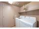 Bright laundry room featuring white washer and dryer set, shelving, and access door at 2528 W Mericrest Way, San Tan Valley, AZ 85144