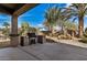 Relaxing back patio featuring an outdoor grill, mature palm trees, and a peaceful rock waterfall feature at 30789 N Raindance Rd, San Tan Valley, AZ 85143