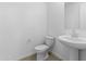 Clean half bathroom featuring pedestal sink, toilet, and neutral tile flooring at 37053 W La Paz St, Maricopa, AZ 85138