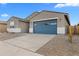 Charming single-story home featuring a blue garage door and desert landscaping at 37053 W La Paz St, Maricopa, AZ 85138