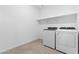 Functional laundry room has modern appliances and shelving for efficient storage at 37053 W La Paz St, Maricopa, AZ 85138