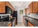 Galley kitchen features black appliances, granite countertops, and wood cabinetry at 5877 N Granite Reef Rd # 2203, Scottsdale, AZ 85250