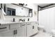 Modern bathroom featuring double sinks, white cabinets, dark fixtures, and a shower with a black-tiled accent wall at 6621 E Sharon Dr, Scottsdale, AZ 85254