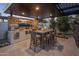 Covered outdoor kitchen with bar seating, a built-in grill, and a dining table for entertaining at 7508 E Laredo Ln, Scottsdale, AZ 85250