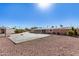 The backyard features a concrete area surrounded by gravel, minimal landscaping, and a glimpse of surrounding houses at 7714 E Calypso Ave, Mesa, AZ 85208