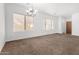Spacious living room featuring neutral carpeting, a modern chandelier, and ample natural light at 7739 E Butte St, Mesa, AZ 85207