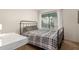 Cozy bedroom with neutral walls, large window, and black metal frame bed with plaid comforter at 8841 S 48Th St # 1, Phoenix, AZ 85044