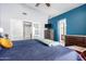 Primary bedroom featuring dual closets, blue accent wall, and a comfy blue bedspread at 9230 W Grovers Ave, Peoria, AZ 85382