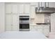 Modern kitchen featuring stainless steel oven and range hood with white shaker cabinets and quartz counters at 10895 E Mission Ln, Scottsdale, AZ 85259