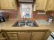 A double basin stainless steel sink with faucet sits below a window with tan countertops and cabinetry at 1281 S Sioux Dr, Apache Junction, AZ 85119