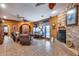 Cozy living room featuring stone fireplace, comfortable seating, and rustic ceiling fan at 14215 E Calle De Las Estrellas Dr, Scottsdale, AZ 85262