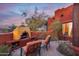 Outdoor kitchen and fireplace with a seating area against a beautiful sunset backdrop at 14215 E Calle De Las Estrellas Dr, Scottsdale, AZ 85262