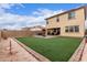 View of backyard with artifical turf, patio, seating, and a block wall with string lights at 16789 W Moreland St, Goodyear, AZ 85338