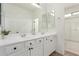 Bright bathroom features a double sink vanity with white cabinets and black hardware, plus a large mirror at 16789 W Moreland St, Goodyear, AZ 85338