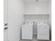 Functional laundry room with a washer, dryer, and shelving for easy organization at 17745 W Carol Ave, Waddell, AZ 85355