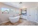 This modern bathroom features a freestanding tub, decorative accent wall, and three windows for natural light at 18430 E Ashridge Dr, Queen Creek, AZ 85142