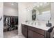 Bathroom with dual sink vanity, neutral walls, and a large walk-in closet at 18434 W Chama Dr, Surprise, AZ 85387