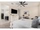 The main bedroom features a white dresser, mounted TV, ceiling fan, and ensuite bath at 18434 W Chama Dr, Surprise, AZ 85387