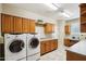 Spacious laundry room featuring front-loading washer and dryer, wood cabinets, and built-in desk area at 29816 N 129Th Gln, Peoria, AZ 85383