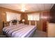 Cozy bedroom featuring a queen bed, dresser, wood paneling, and sheer curtains for ample natural light at 303 S Recker Rd # 152, Mesa, AZ 85206