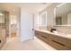 Bright bathroom featuring dual sinks, modern vanity, lighted mirrors and a glass shower door at 5000 N Camelback Ridge Dr # 304, Scottsdale, AZ 85251