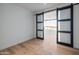 A bright bedroom featuring a light wood floor, a barn door, and views of the outdoor balcony at 5000 N Camelback Ridge Dr # 304, Scottsdale, AZ 85251