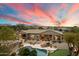 Expansive property features a pool, putting green, and mountain views at sunset at 6626 E Oberlin Way, Scottsdale, AZ 85266